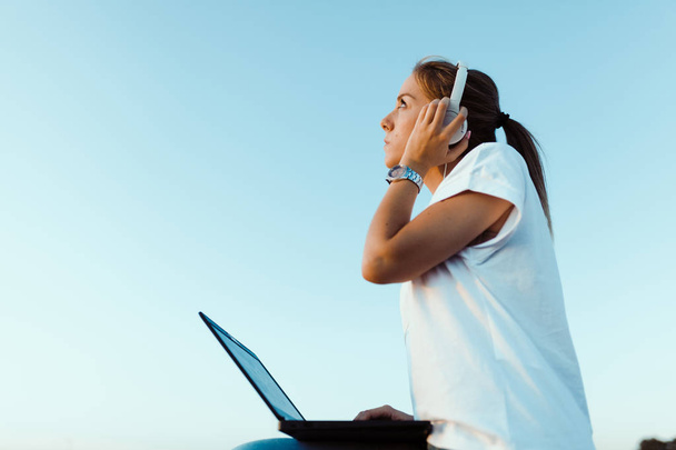 Jeune femme avec son ordinateur portable écouté des communications externes - Photo, image