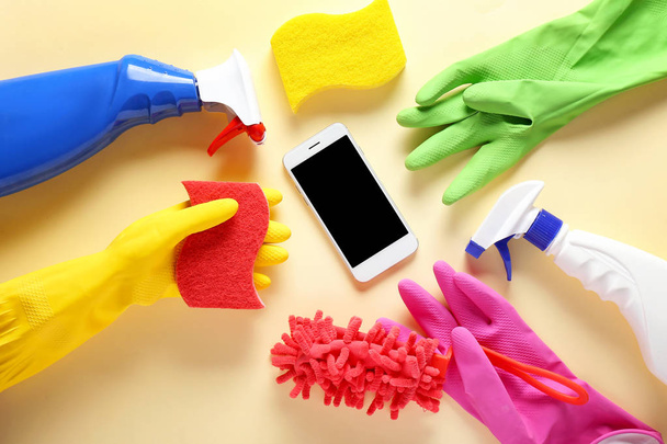 Cleaning supplies and mobile phone on color background - Photo, Image