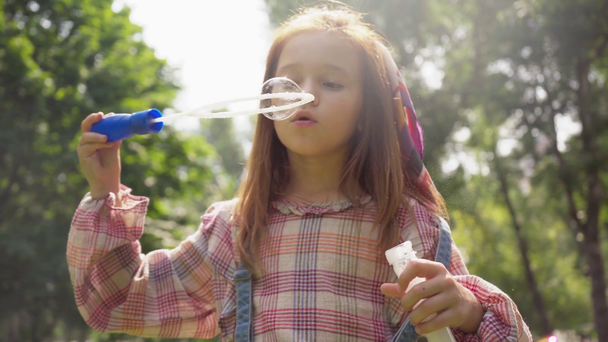 lindo pelirroja niño soplando jabón burbujas en soleado parque
 - Imágenes, Vídeo