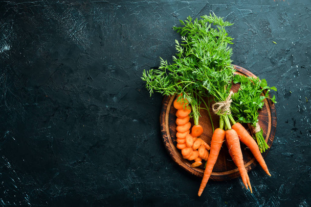 Fresh carrots on a black stone background. Top view. Free space for your text. - Фото, зображення