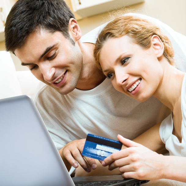 Cheerful couple paying by plastic card - Foto, imagen