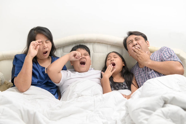 Πατέρας και μητέρα με παιδιά που χασμουριέται και τεντώνεται στο κρεβάτι, - Φωτογραφία, εικόνα