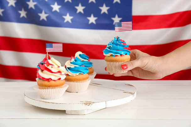 Woman taking tasty patriotic cupcake from table - Фото, изображение