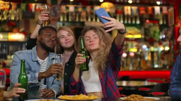 Freunde machen Selfie mit Smartphone in Bar. Junge Leute posieren, lachen und reden. Bierflaschen und. Freunde machen Selfie mit Smartphone. - Filmmaterial, Video
