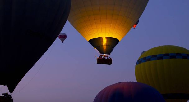 壮大なカッパドキアの上を飛ぶ熱気球 - カッパドキアの丘で熱気球を見ている女の子 - 写真・画像