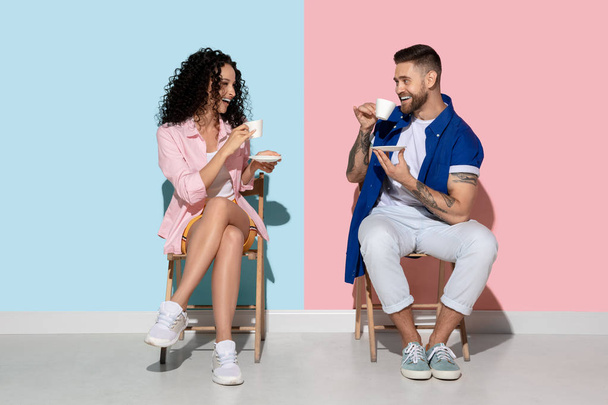 Young emotional man and woman on pink and blue background - Fotó, kép