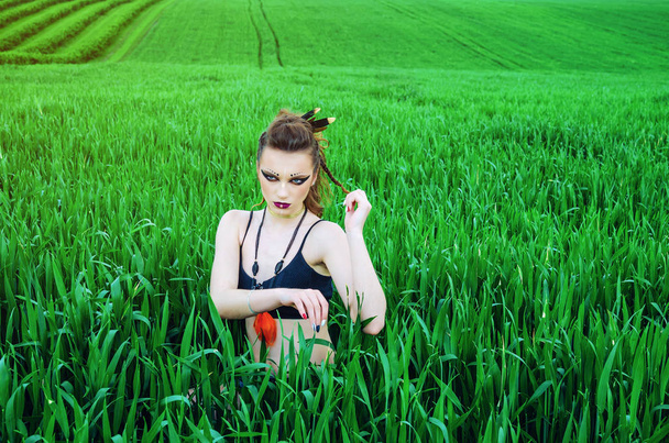 Agressieve make-up meisje, Amazon karakter in een groene tarwe veld. - Foto, afbeelding