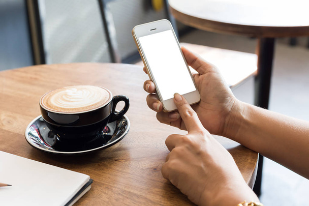 Рука женщина с помощью телефона, пустой экран смартфон на деревянном столе в кафе, с вырезкой пути
 - Фото, изображение