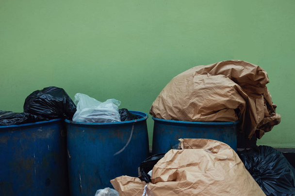 Poubelle et poubelle contre le mur vert. Pollution Problème de non-tri des déchets Concept de comportement
 - Photo, image