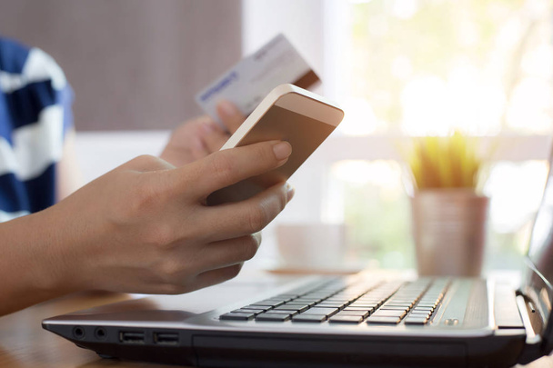 Женщина держит в руках кредитную карту и с помощью смартфона с ноутбуком компьютер Интернет торговый концепт
 - Фото, изображение