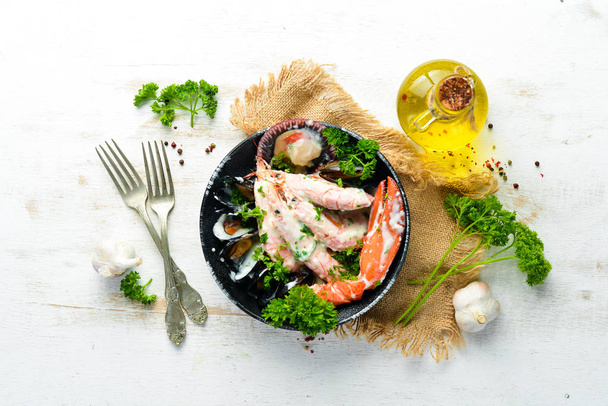 Boiled Seafood in a creamy sauce on a black stone plate. Seafood, prawns, shellfish, lobster. Top view. Free copy space. - 写真・画像