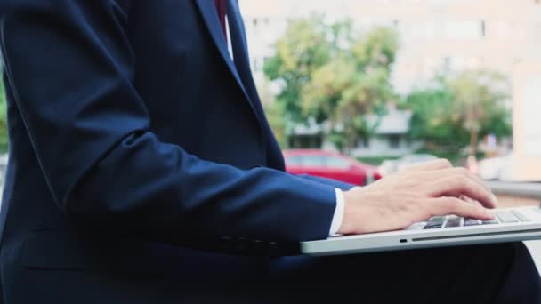 Manger in business suit typing on laptop keyboard outdoor in the city, close up zoom in shot - Materiał filmowy, wideo