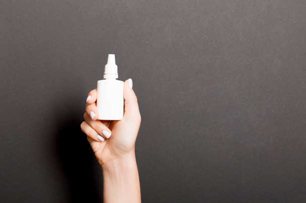 Les mains féminines tiennent bouteille de médicament pulvérisation nez sur fond noir isolation
 - Photo, image