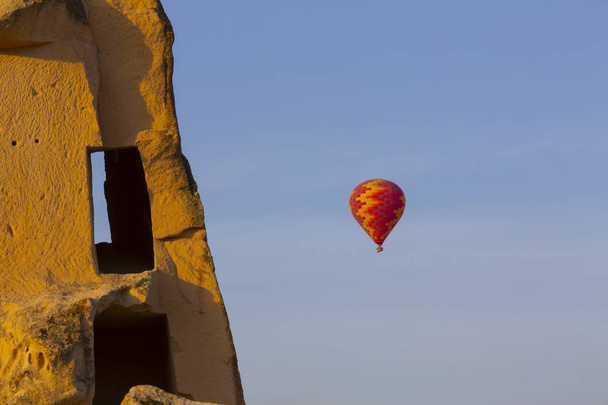 Heißluftballon fliegt über spektakulärem Kappadokien - Mädchen beobachten Heißluftballon auf dem Hügel von Kappadokien - Foto, Bild