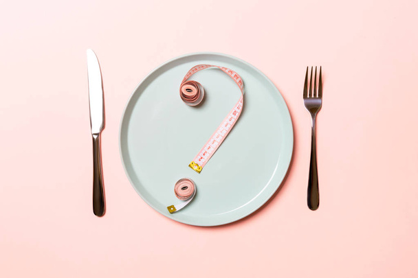 ピンクの背景に丸いプレート上のテープを測定することで作られた質問マーク。ためらいと食事の概念のトップビュー - 写真・画像