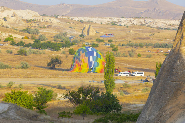 Hot air balloon flying over spectacular Cappadocia - Girls watching hot air balloon at the hill of Cappadocia - Photo, Image
