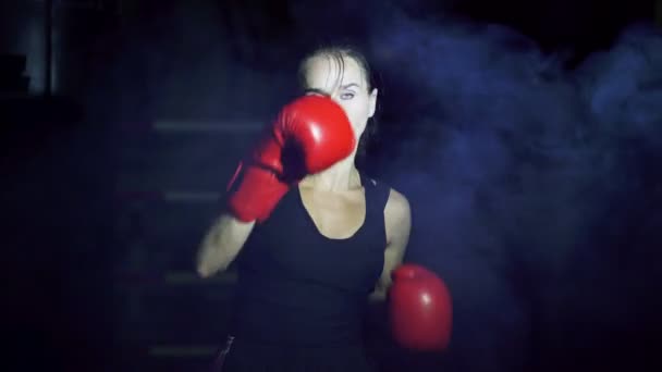 Konzept des Boxens. Boxerin kämpft mit Schatten im Rauch, dunkle Trainingshalle.  - Filmmaterial, Video