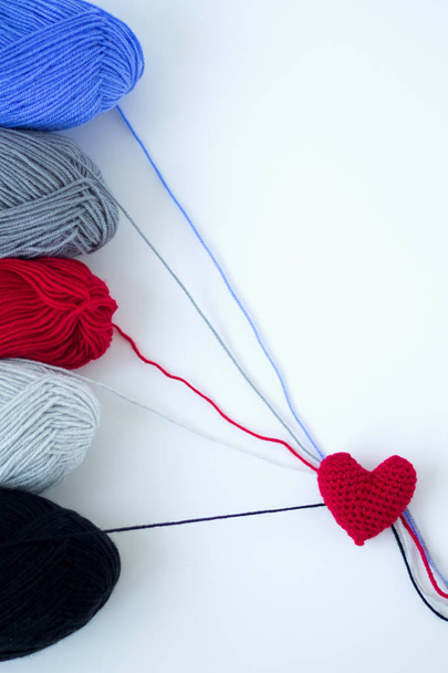 colored skeins of yarn and a red knitted heart on a white background - Photo, Image