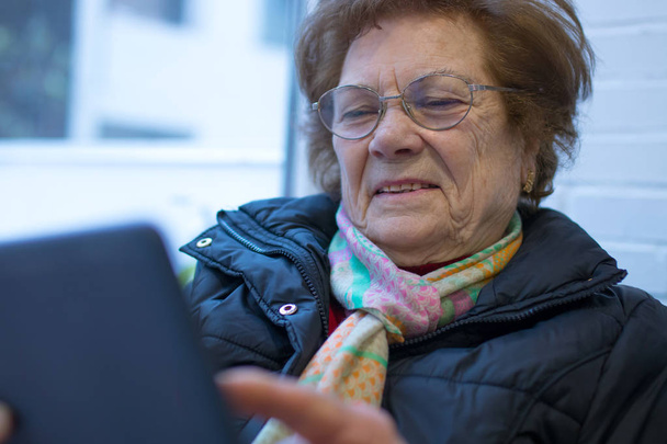 vanhempi nainen tai isoäiti digitaalisen tai kannettavan tabletin kanssa
 - Valokuva, kuva