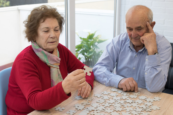 casal mais velho fazendo quebra-cabeça na mesa
 - Foto, Imagem