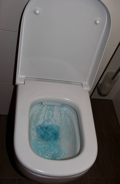 バスルームに青い水が立ち上るトイレの総ビュークローズアップとマルチカラーで撮影 - 写真・画像