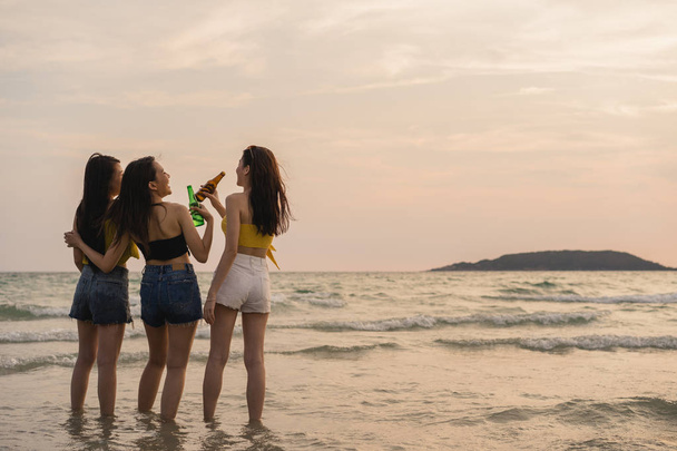 Gruppe asiatischer Teenagermädchen, die am Strand feiern, Freunde, die gerne Bier am Strand trinken, wenn die Sonne untergeht. Outdoor-Aktivitäten Freunde reisen Urlaub Sommer-Konzept. - Foto, Bild