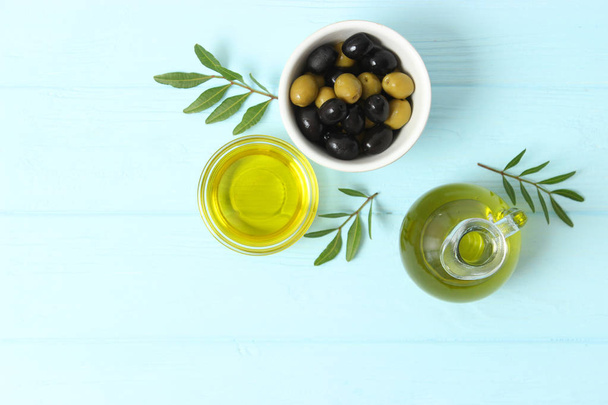 olio d'oliva, foglie verdi e olive in tavola. - Foto, immagini
