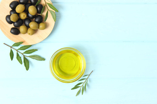 oliwa z oliwek, zielone liście i oliwki na stole. - Zdjęcie, obraz
