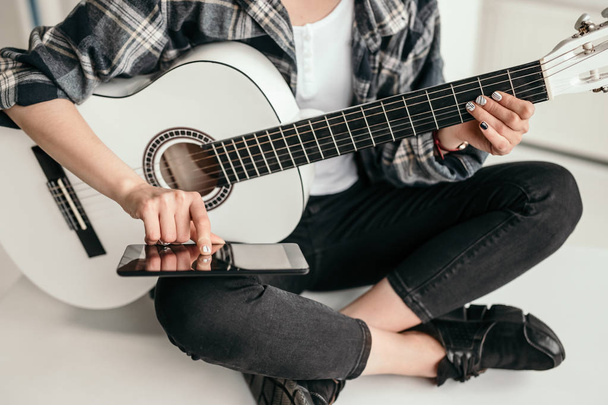 Crop woman with smartphone learning to play guitar - Foto, afbeelding