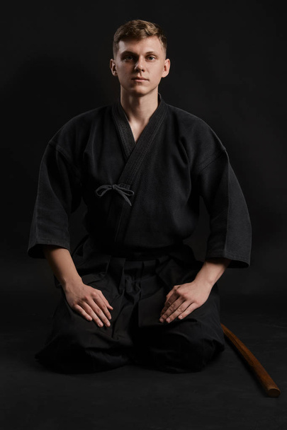 Geleneksel Japon kimonosu giymiş Kendo gurusu Shinai bambu kılıcıyla siyah bir stüdyoda dövüş sanatları eğitimi alıyor.. - Fotoğraf, Görsel