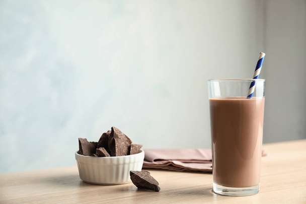 Glass of tasty chocolate milk on wooden table, space for text. Dairy drink - Фото, изображение