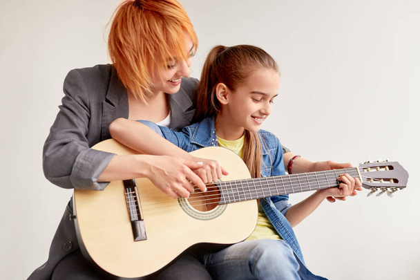 Diligent girl learning playing guitar with individual teacher - Photo, Image