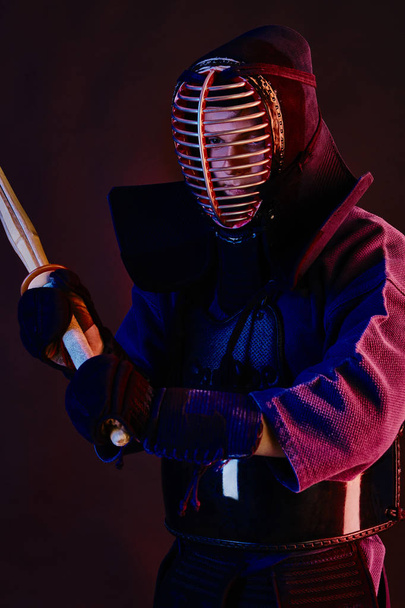Зблизька стрілянина, боєць Кендо, одягнений в обладунки, традиційний кімоно, шолом практикує бойове мистецтво з шинайським бамбуковим мечем, чорний фон. - Фото, зображення