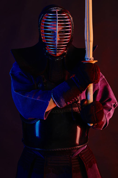 Close up shot, Kendo lutador vestindo em uma armadura, quimono tradicional, capacete praticando arte marcial com espada de bambu shinai, fundo preto
. - Foto, Imagem