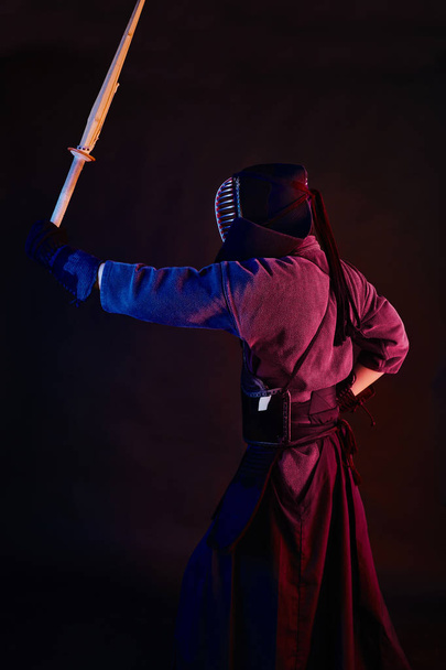 Lähikuva ammuttu, Kendo taistelija yllään haarniska, perinteinen kimono, kypärä harjoitellaan kamppailulaji shinai bambu miekka, musta tausta
. - Valokuva, kuva