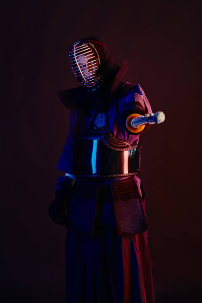 Close up shot, Kendo fighter wearing in an armor, traditional kimono, helmet practicing martial art with shinai bamboo sword, black background. - Fotoğraf, Görsel