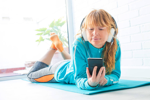 woman in sportswear listening to music with phone and headphones - Valokuva, kuva