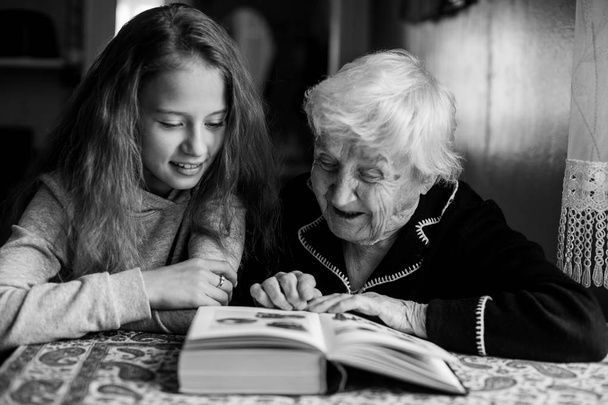 La anciana le está leyendo un libro a su amada nieta. Foto en blanco y negro
. - Foto, Imagen