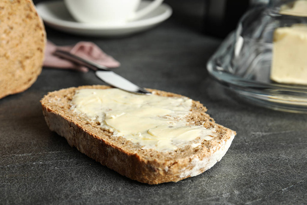 Slice of tasty bread with butter on dark table - 写真・画像