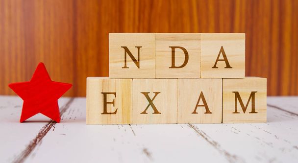 Концепция экзамена NDA проводится в Индии для набора на деревянные блочные буквы
. - Фото, изображение