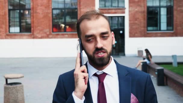 Επιχειρηματίας σε κοστούμι περπάτημα και μιλάει στο τηλέφωνο μπροστά από την επιχειρηματική περιοχή - Πλάνα, βίντεο