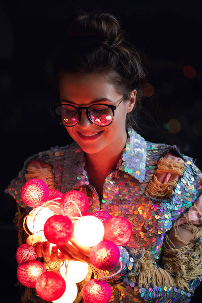 Happy woman wearing glowing jacket with sequins is holding light - Foto, imagen
