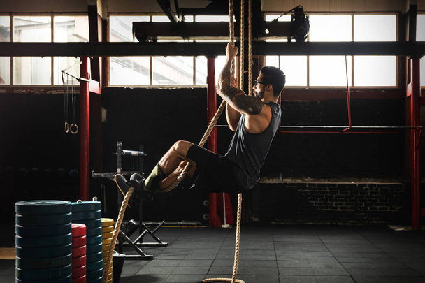 Sportsman doing rope climbing exercise - Фото, зображення
