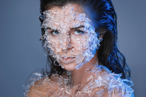 Female face covered with a lot small pieces of glass or ice - 写真・画像