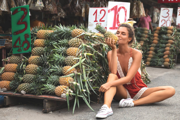 Young and happy woman with a pile of pineapples on the local Tha - Photo, Image