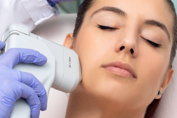 Draufsicht der Frau mit kosmetischer Gesichtsbehandlung hoher Intensität fokale Ultraschallbehandlung. - Foto, Bild