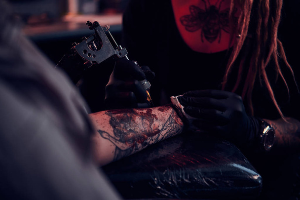 Proces tatuażu makining w ciemnym studiu tatuażu. - Zdjęcie, obraz
