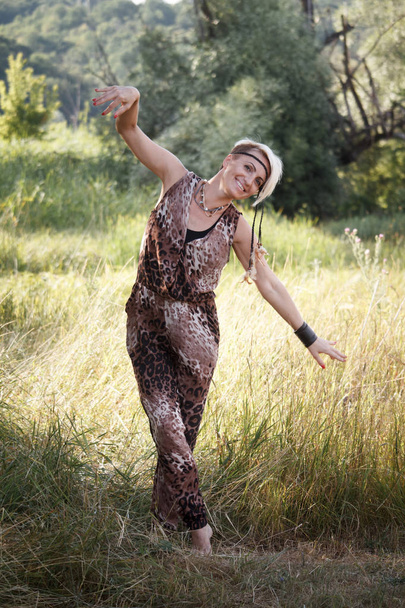 Close-up adult woman blonde dances and enjoys life on a background of grassy meadow, selective focus - Photo, Image
