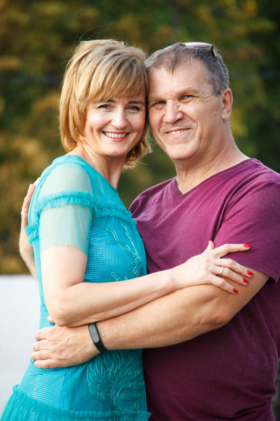Middle-aged couple smiling and hugging on a city street, selective focus - Photo, Image