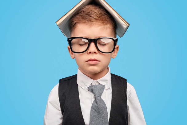 Little boy with opened book on head and in glasses - Foto, Imagen